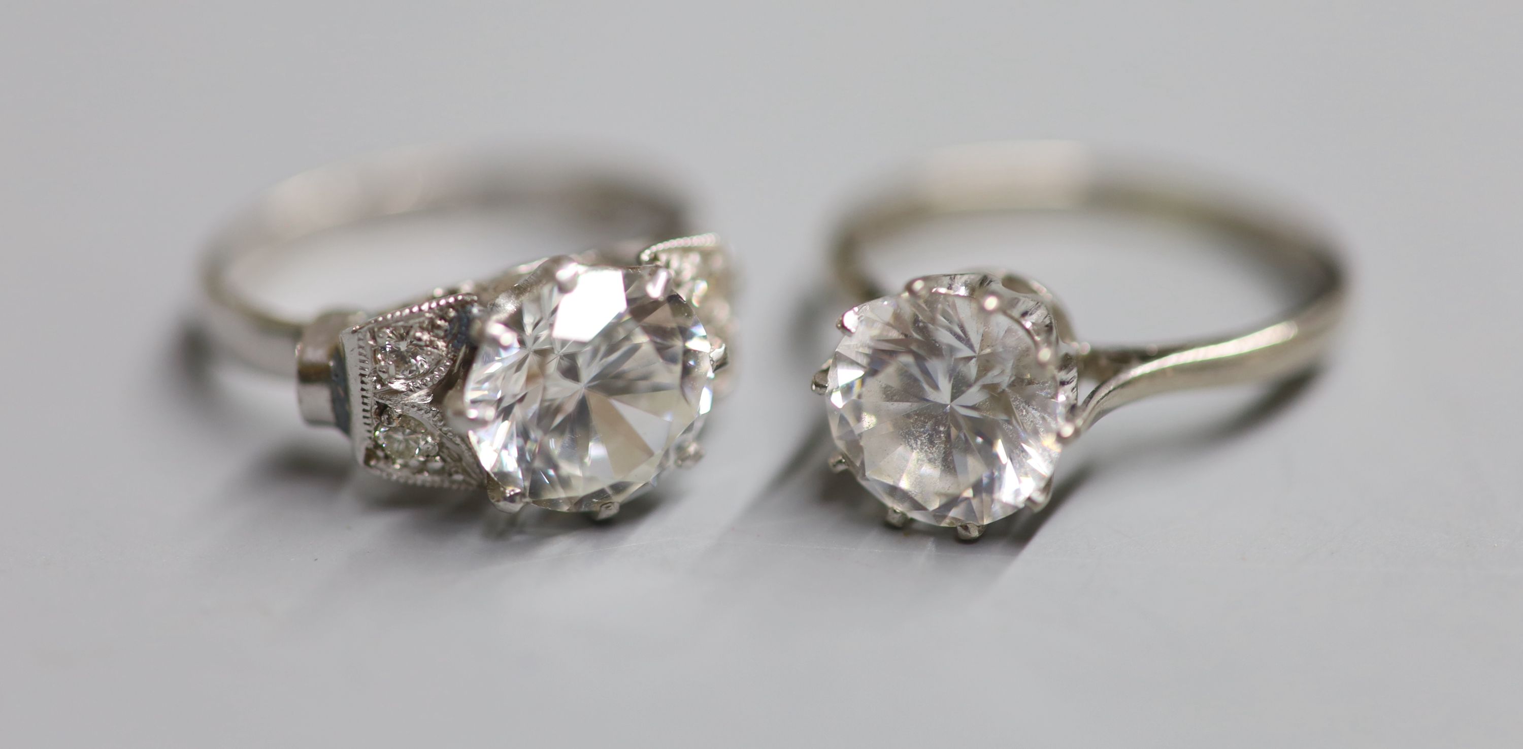 A white metal (stamped plat) single stone moissanite? and four stone diamond set dress ring and an 18ct gold